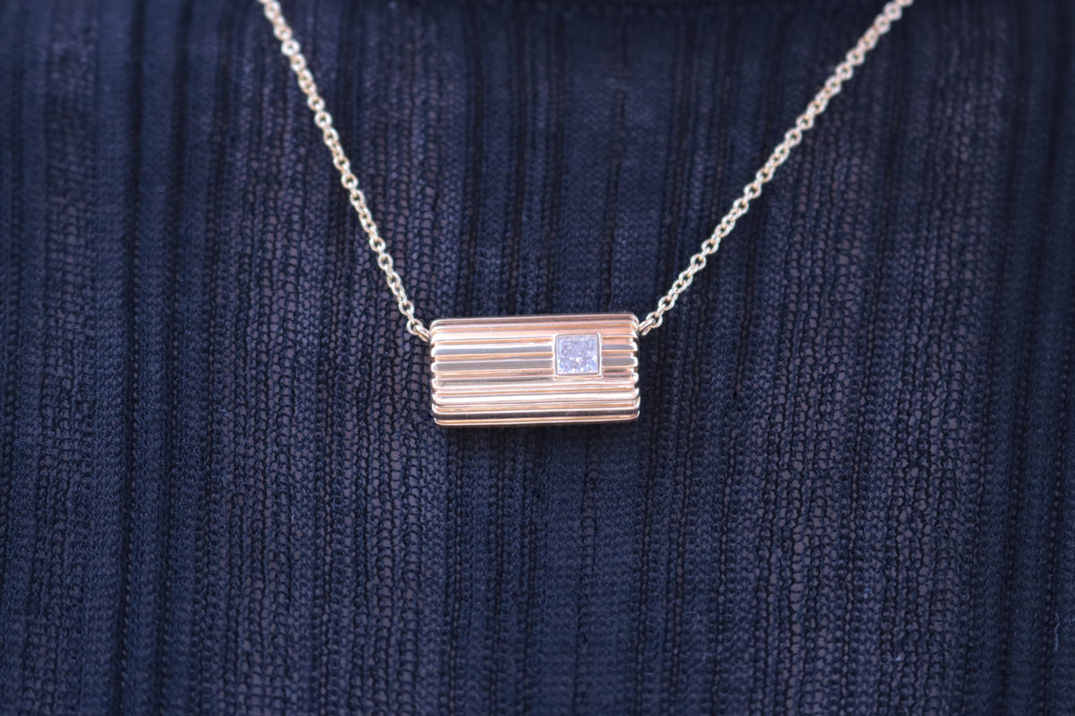 Lettre Douce diamond necklace in solid 18k yellow gold, close-up on the body against a dark textured knit #Gemstone_Diamond