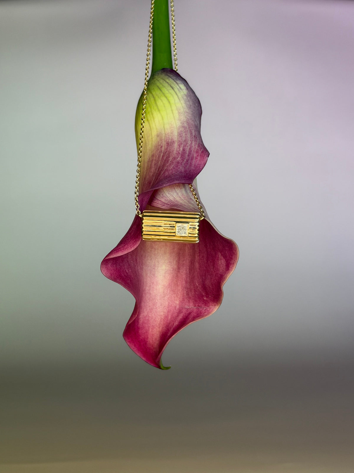 Lettre Douce diamond necklace in solid 18k yellow gold, suspended against a calla lily #Gemstone_Diamond
