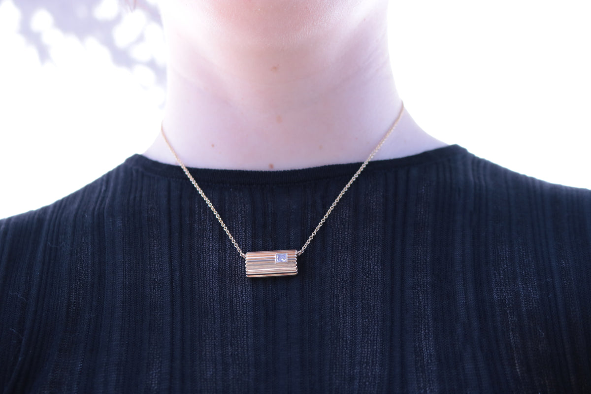 Lettre Douce diamond necklace in solid 18k yellow gold, shown worn at the collarbone for scale #Gemstone_Diamond
